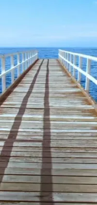 This live phone wallpaper showcases a wooden bridge spanning a serene body of water in full daylight