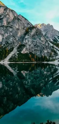 This live wallpaper showcases a mesmerizing natural scenery of a serene body of water surrounded by towering mountains in the background