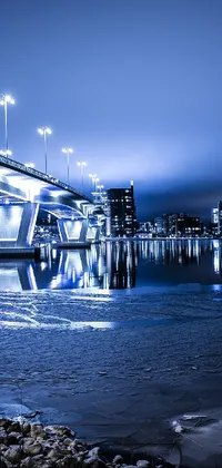 This live phone wallpaper displays a stunning bridge by a body of water at night, showcasing cold blue tones and urban city photography
