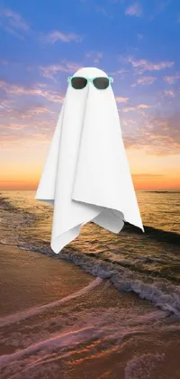 This stunning phone live wallpaper features a serene beach scene with a white towel resting on the sand, paired with an imaginative Halloween twist