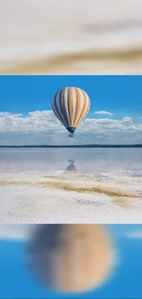 This fantastic phone live wallpaper showcases a beautiful hot air balloon flying gently over a serene body of water