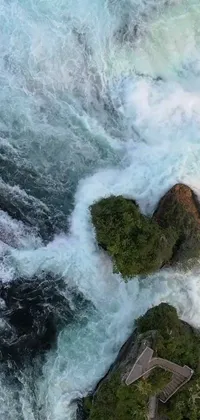 This stunning phone live wallpaper captures the beauty of nature with two rocks sitting on a river