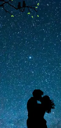 This breathtaking phone live wallpaper features a romantic and dreamy scene of a couple kissing under a sprawling tree in the starry night sky