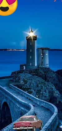 This live wallpaper features a blue nighttime scene with a car parked on a bridge by a lighthouse, illuminated by the light from the lighthouse and the car's headlights