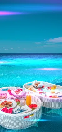 This vibrant live wallpaper for your phone features two trays of delicious breakfast food on top of a crystal-clear swimming pool with a stunning turquoise ocean view