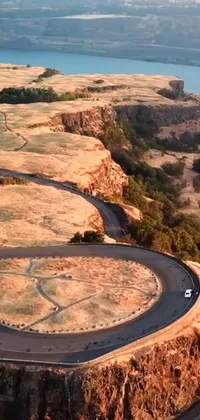 This phone live wallpaper showcases an aerial shot of a captivating winding mountain road with cliffside views