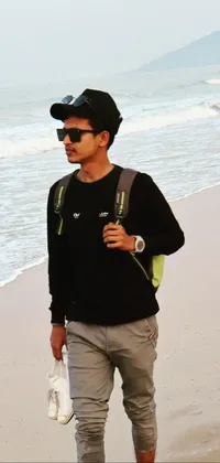 This live wallpaper shows a man walking along the beach next to the ocean wearing sunglasses and a cap, giving a casual and confident vibe