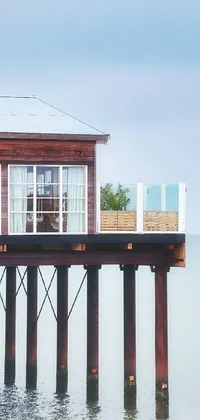 This phone live wallpaper showcases a beautiful seaside scene with a building on stilts resting on a pier