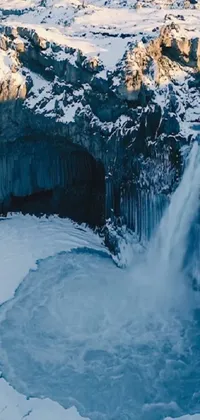 This live wallpaper for smartphones showcases a breathtaking snowy waterfall scene nested between snow-covered trees