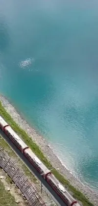 Bring the excitement of a steel train right to your phone's wallpaper with this live background of a long train on a winding steel track near a beautiful body of water