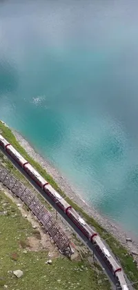 This phone live wallpaper features a long train on a steel track, situated near a picturesque body of water