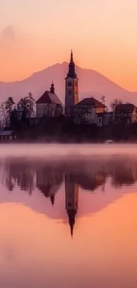Looking for a serene and relaxing live wallpaper for your phone? Look no further than this stunning image of a church in the middle of a peaceful lake surrounded by mountains