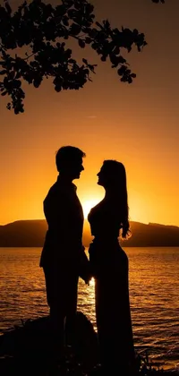 This stunning live phone wallpaper depicts a romantic couple gazing at a beautiful sunset