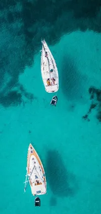 This phone live wallpaper depicts two boats drifting peacefully on turquoise waters with sunny skies and distant islands in the background