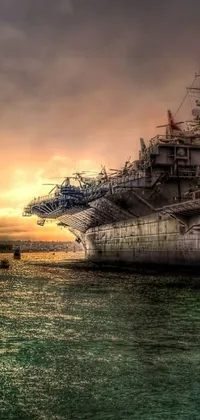 Looking for a stunning live wallpaper for your smartphone? Check out this breathtaking image of an aircraft carrier sitting atop a body of water at sundown