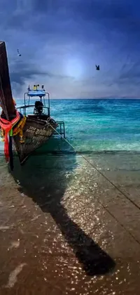 This delightful live wallpaper features a serene coastal setting with a fishing boat resting on the golden sand beach alongside turquoise waters