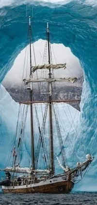 This breathtaking phone live wallpaper depicts a peaceful sailboat gently floating on bright blue waters set in an icy cavern