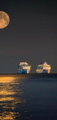 This breathtaking phone live wallpaper showcases a peaceful and serene scene with two ships sailing in the calm waters under a clear night sky and a full moon shining brightly in the background