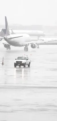 This airport tarmac phone live wallpaper features a large commercial jetliner during a hail storm in New York City