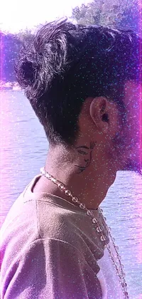 This live wallpaper features a confident man sporting edgy tattoos and facial piercings standing in front of a serene body of water wearing Assamese traditional attire, including a choker