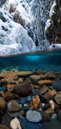 This live wallpaper showcases a serene body of water surrounded by rocks and snow, perfect for hyperrealism lovers