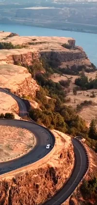 This lively and engaging live wallpaper features a car cruising along a winding road in the midst of breathtaking natural surroundings