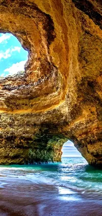 This stunning live phone wallpaper depicts a panoramic view of a serene beach and cave