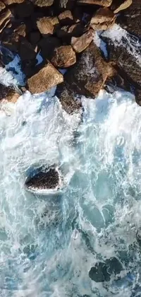 This live wallpaper depicts a stunning bird's eye view of a body of water surrounded by rocky terrain