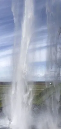 This phone live wallpaper showcases a hyperrealistic image of a geyser in Iceland, set against a Hurufiyya landscape