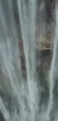 This phone live wallpaper provides a mesmerizing view of a man gliding through the sky with a stunning waterfall in the background