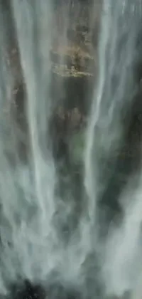 This phone live wallpaper portrays a group of people admiring a stunning waterfall in a detailed matte painting