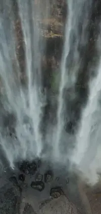 This stunning phone live wallpaper showcases a group of people standing in front of a beautiful waterfall