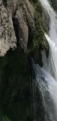 Looking for an extraordinary live wallpaper for your phone? Check out this captivating image of a man riding a wave on top of a waterfall