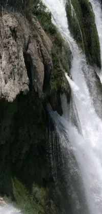 Looking for an exciting and unique live wallpaper for your phone? Check out this stunning image of a brave rider surfing a massive wave cascading down a waterfall
