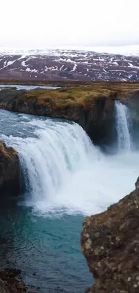 The nature-inspired phone live wallpaper offers a serene and calming view of a waterfall that flows down the rocks, surrounded by a vast body of water