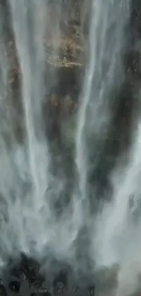 This phone live wallpaper depicts a group of people enjoying the natural beauty of a stunning waterfall