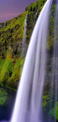 This live wallpaper showcases a captivating waterfall at the heart of a lush green field, with a tilt shift effect adding an artistic flair