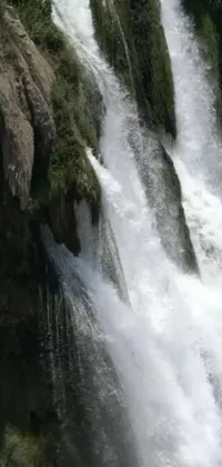 This phone live wallpaper depicts a thrilling scene of a man riding a wave on top of a waterfall