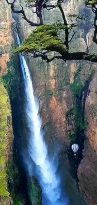This phone live wallpaper depicts a hot air balloon sailing past a gorgeous waterfall, set against a stunning African backdrop