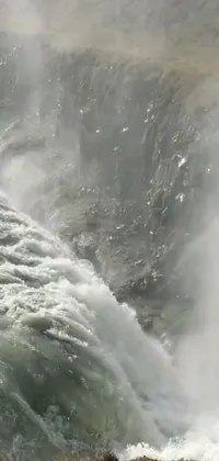 This phone live wallpaper depicts a breathtaking scene - a man standing near a stunning waterfall