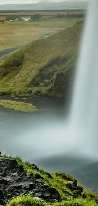 This stunning live wallpaper features a lush green hillside where a herd of sheep is grazing, while a waterfall cascades down a cliff into a serene lake in the distance