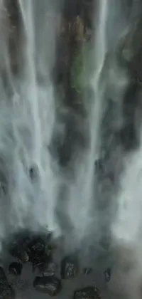 This live wallpaper offers a scenic view of a waterfall surrounded by people in a style marked by hurufiyya