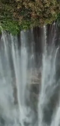 Enhance your device with this striking phone live wallpaper, capturing the breathtaking aerial view of a glistening waterfall