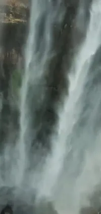 Looking for a stunning live wallpaper for your phone screen? Check out this beautiful hurufiyya-style image of a man standing in front of a breathtaking waterfall