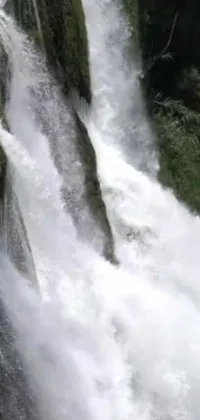 This phone live wallpaper showcases an incredible image of a surfer riding a massive wave on top of a stunning waterfall