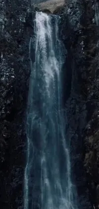 This stunning phone live wallpaper showcases a breathtaking waterfall cascading down a cliff amidst a lush forest