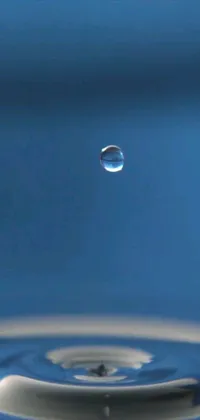This live wallpaper features a serene scene of a water droplet falling into a pool of water, surrounded by a blue sky with a moon in the background