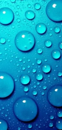 This phone live wallpaper showcases a stunning close-up of water droplets on a smooth blue surface, giving the illusion of a body of water