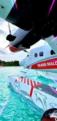 This phone live wallpaper features a stunning red and white plane perched atop a pristine body of crystal-clear blue water