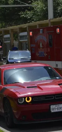 Looking for a lively live wallpaper? Check out this red fire truck driving down the street next to a white car, with a Texas-inspired hospital in the background